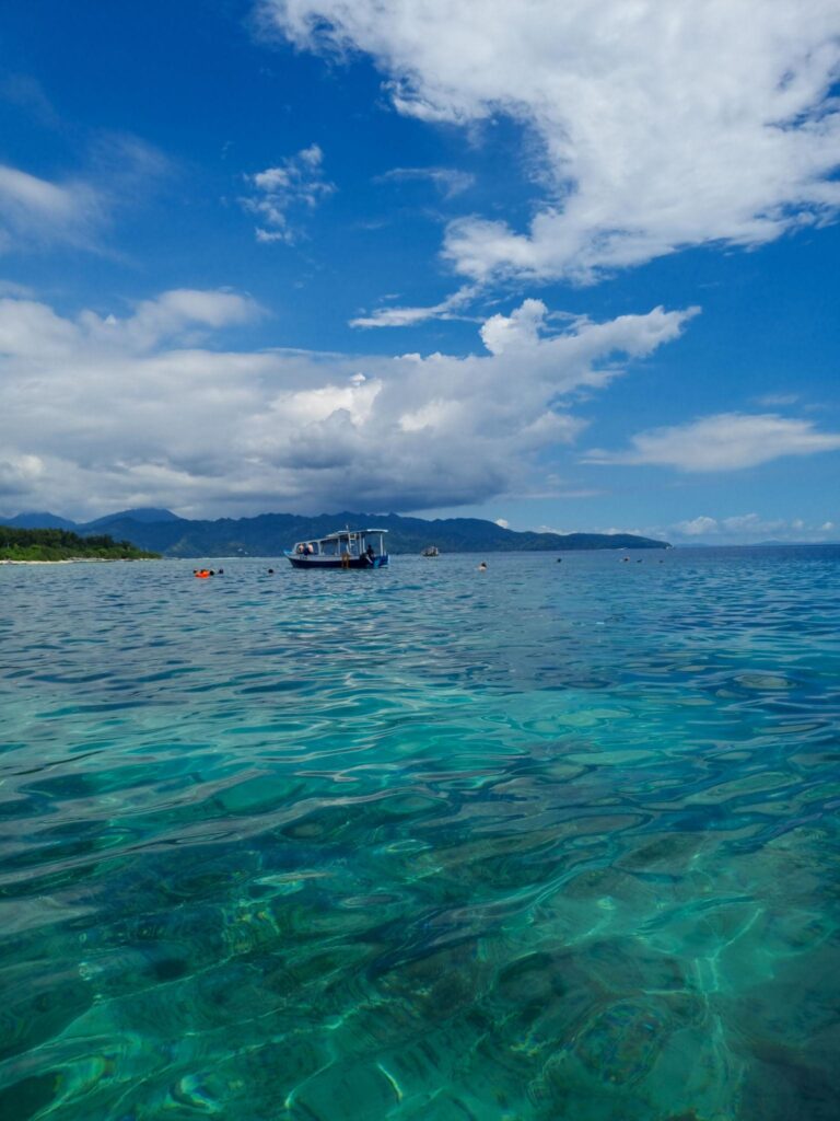 Wisatawan snorkeling di Gili Petelu Lombok dengan terumbu karang dangkal dan ikan warna-warni