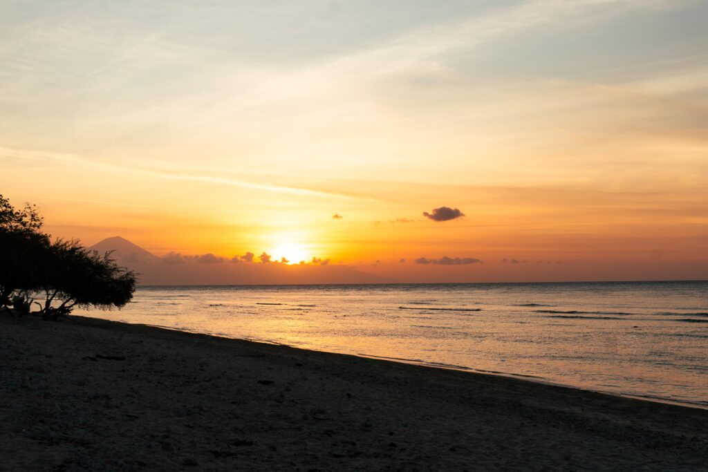 Matahari terbenam di Gili Trawangan dengan siluet ayunan pantai dan langit oranye