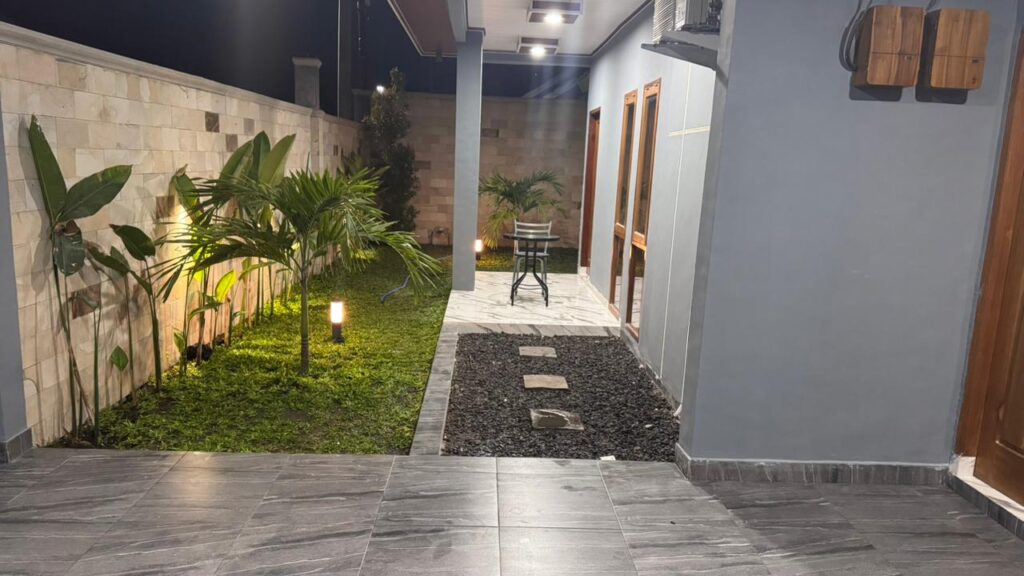 Teras villa Lombok dengan taman kecil dan pencahayaan malam yang hangat